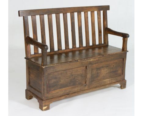 Victorian pine box settle, slat back, open arms, the seat with a central lift up lid, two recessed panel front, raised on bra