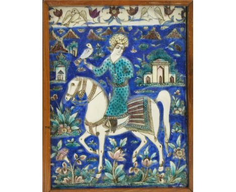 Qajar tile, mid 19th Century, moulded in low relief with a hunter on horseback, finished in underglaze blue, turquoise and au