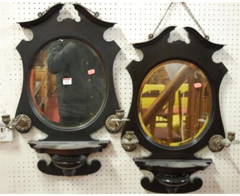 A pair of Edwardian ebonised bevelled wall mirrors, each having integral shelf and twin moveable brass candle sconces 