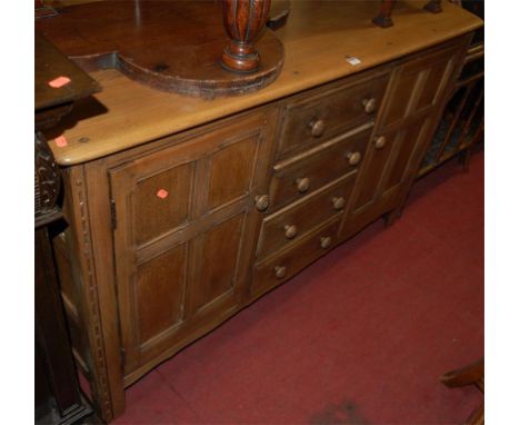 An Ercol light elm sideboard having four central drawers flanked by cupboard doors (recently stripped)