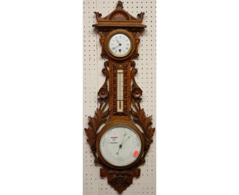 An early 20th century carved oak aneroid clock barometer 