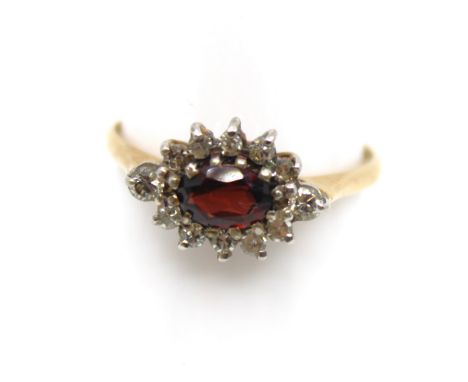 9ct Gold Garnet and Diamond Cluster Ring.  The ring contains an Oval Brilliant Cut Garnet that measures approx. 6mm in length
