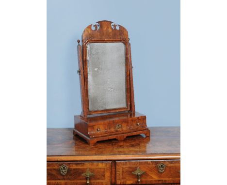 A George II walnut dressing mirror, circa 1740, the arched mirror section decorated with fret cut foliate motifs, the cavetto