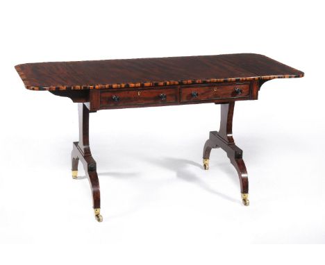 A Regency mahogany and coramandle banded sofa table, circa 1815, the rectangular top with two hinged leaves, above two frieze