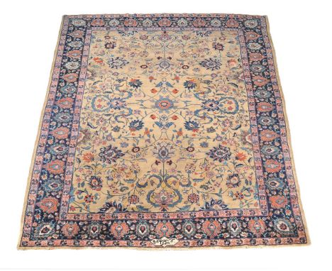 A Tabriz carpet, the ochre field decorated in polychrome throughout with flowering foliage, within a navy border decorated wi