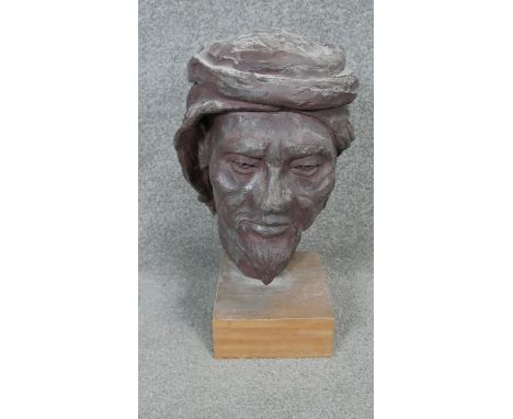 A sculpted ceramic head of a bearded man in a turban mounted on a wooden base. H.45cm 