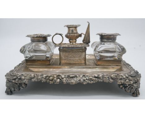 A Georgian silver desk stand with two silver foliate design glass inkwells and silver chamber stick with snuffer. Hallmarked: