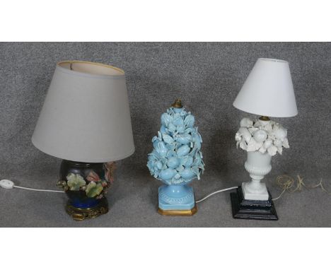 A collection of three ceramic floral design table lamps. One hand painted with relief hollyhocks on a gilt metal pierced base