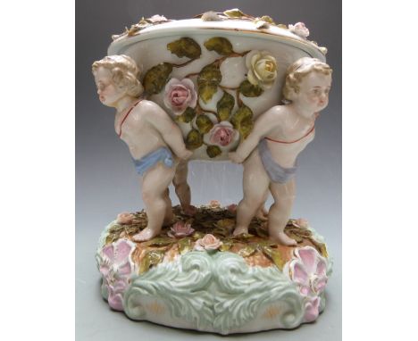 German figural porcelain oil lamp supported by four putti and decorated with applied flowers, blue hatched mark to base, prob
