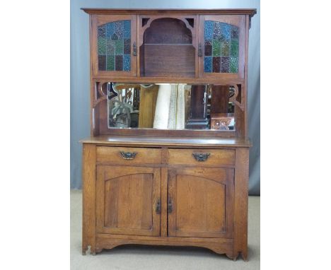 Arts and Crafts oak dresser, the top having two cupboards with leaded glass doors over a bevelled edge mirror, the base fitte