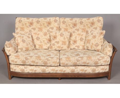 An Ercol 'New Renaissance' Three seat sofa in Golden Dawn finish, with light brown and cream floral upholstery. Complete with