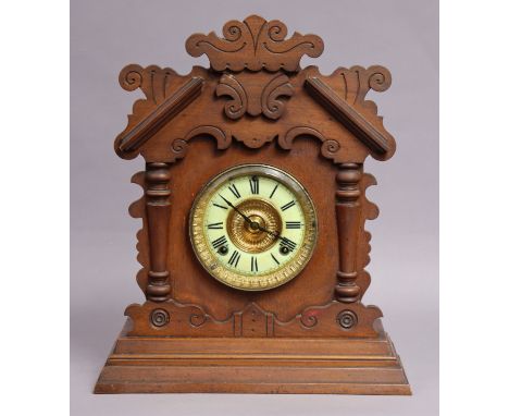 A late 19th century American Gingerbread mantel clock by the Ansonia Clock Co., having black roman numerals to the white enam