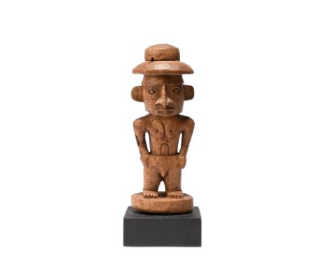 A Humboldt Bay amulet figure Papua New Guinea the standing male figure wearing a hat, 11.6cm high, on a stand. (2)