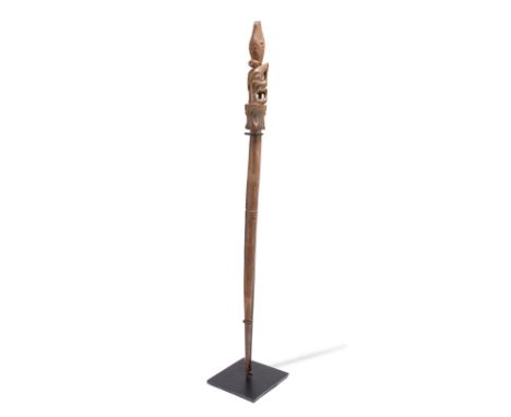 A Dayak pig stick tun tun Indonesia with a carved seated ancestor figure finial, 52.5cm long, on a stand. (2)