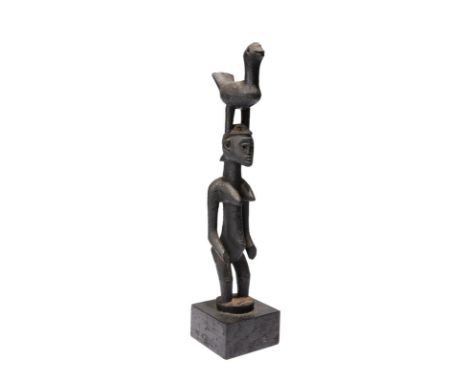 A Senufo standing female figure Ivory Coast with a bird crest and having a black oily patina, probably a staff finial, 26cm h