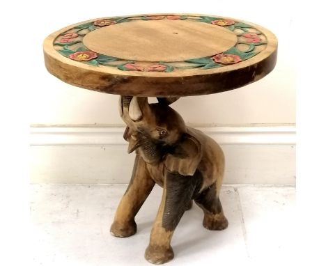 Indian carved teak circular side table with carved floral decoration to top, the base having a carved elephant with raised tr