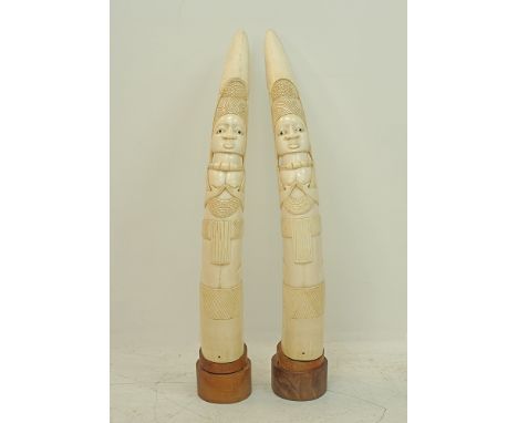 A pair of carved ivory African tusks depicting figures of women holding their breasts, L86cm, approx.weight:6360g and 6450g. 