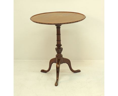 A carved mahogany round lipped and tilt top table, the top made of three planks and raised on a turned tripod pedestal, H67cm