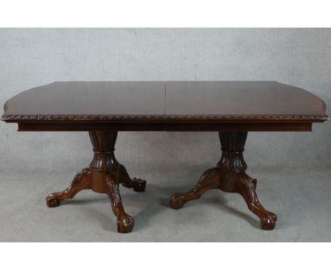 A Victorian style mahogany twin pillar dining table with heavily carved columns each on three outswept supports terminating i