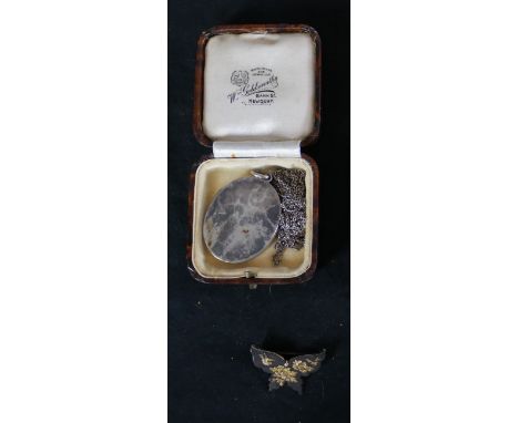 A hammered silver oval locket and chain along with a Shakudo ware butterfly brooch with gilded peony and song bird design. Lo