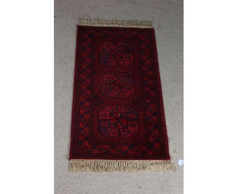 Super Keshan carpet, the red ground with triple elephant foot lozenge pattern centre and tasselled ends, 136cm x 69cm