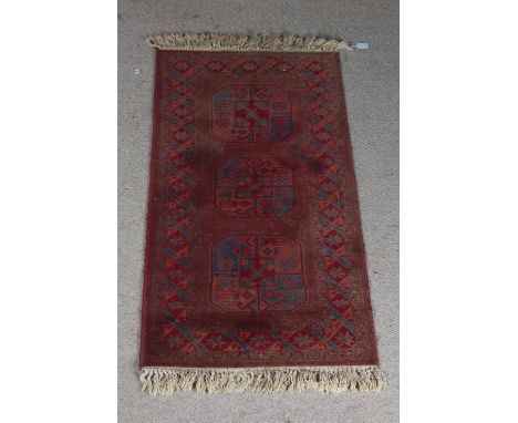 Super Keshan carpet, the red ground with triple elephant foot lozenge pattern centre and tasselled ends, 136cm x 69cm