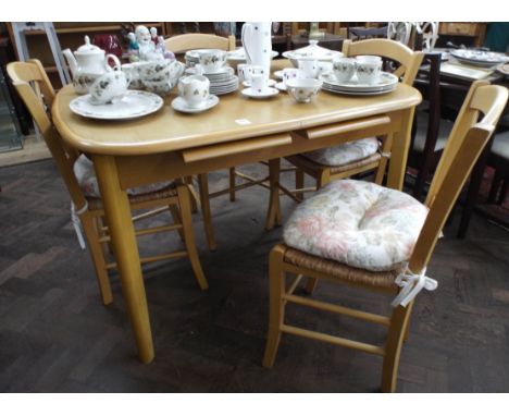 A modern light beech extending dining table with centre leaves and four similar rush seat chairs 