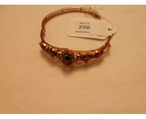 A yellow metal bangle inset with garnets and seed pearls