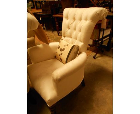A pair of Victorian style button-back armchairs with scrolled backs and serpentine over stuffed seats raised on turned suppor
