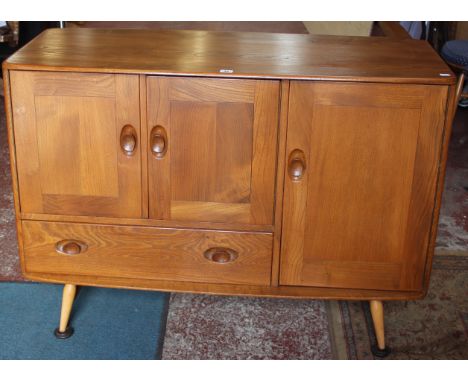 An Ercol elm sideboard with shelved superstructure with cupboards and drawers below on splayed spindle legs 133cm high, 114cm