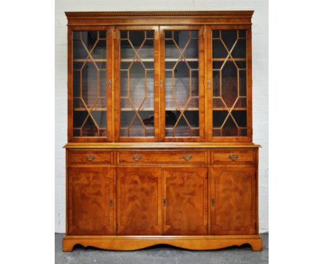 Modern yew wood bookcase, dentil moulded cornice, plain frieze, astragal glazed doors enclosing two adjustable shelves, three