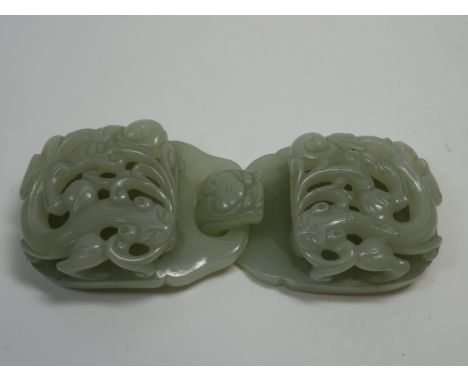 A jade buckle18th/19th centuryof plae green tone and formed of two linking oval panels, each carved and pierced in relief wit