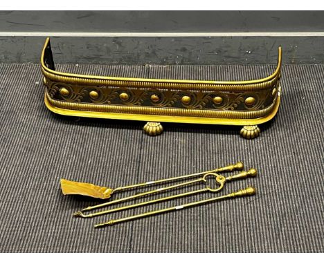 A Victorian brass fender, 90cm wide, with a set of three fire tools to include a poker, tongs and shovel