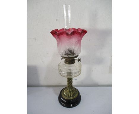 A Victorian oil lamp with twist brass column and cranberry glass shade