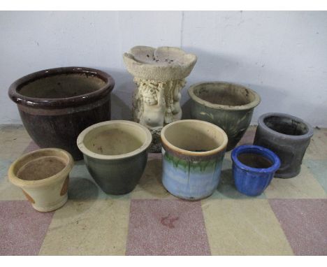 A concrete birdbath along with various ceramic garden pots