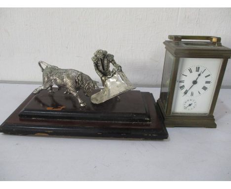A French brass carriage clock ( one glass panel missing) along with a white metal group of a bullfighter and bull