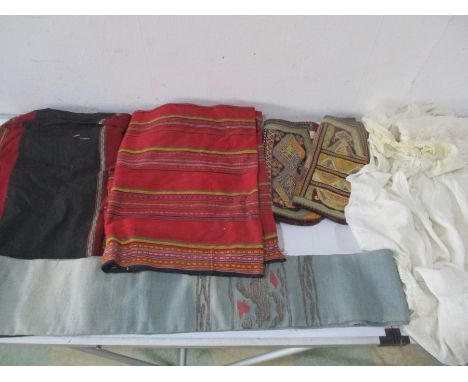 A Japanese sash with metal thread, two babies christening gowns, two Laos tribal textiles, a pair of Skopje leg covering etc