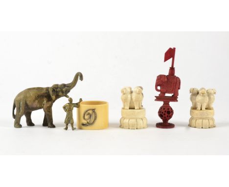 A brass study of an elephant,  with outstretched trunk, height 7cm, together with a pair of bone carvings of mystical beasts 