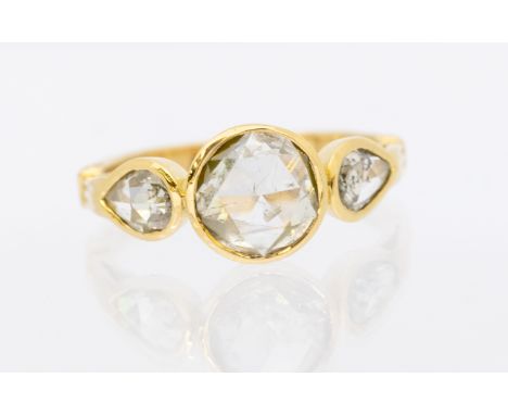 A diamond and gold three stone ring, comprising a central round mixed rose cut diamond, measuring approx 7.7mm, with a single