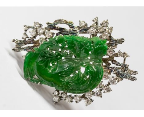 A diamond and jadeite white metal pendant/brooch, comprising a carved bird, with a bark like border claw set with small round