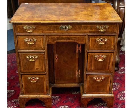 A George II walnut veneered kneehole desk, rectangular moulded top above frieze drawer and central recessed cupboard door enc