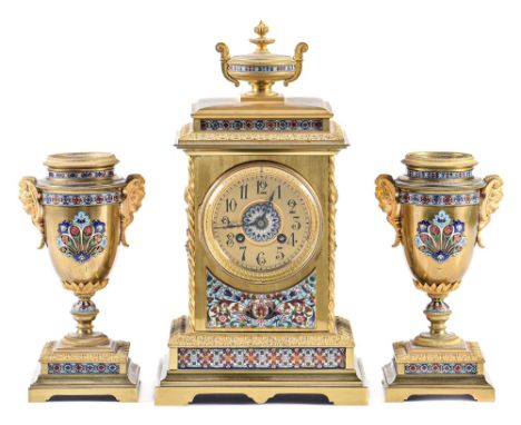 A French brass and champleve enamel garniture de cheminee, late 19th c, the pillar shaped clock surmounted by an urn, the sid