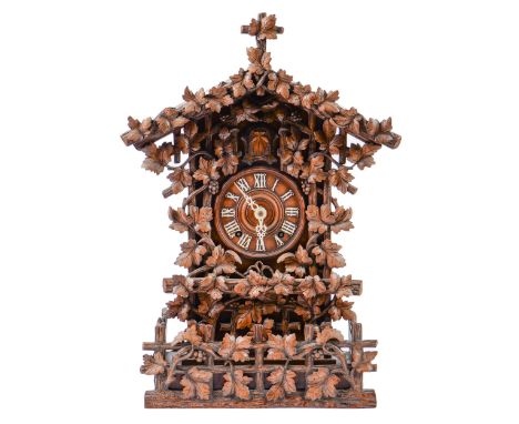 A Swiss walnut cuckoo clock, late 19th c, in the form of a chalet embowered with fruiting vines centred by the turned chapter