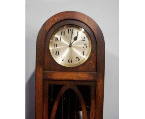 An early 20th century oak Longcase Clock, arch top, silvered circular dial with Arabic numerals, glazed door enclosing three 