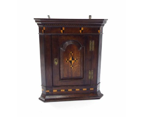 19th century small oak hanging corner cupboard, the single arched panelled door enclosing a serpentine shelf, with shield inl