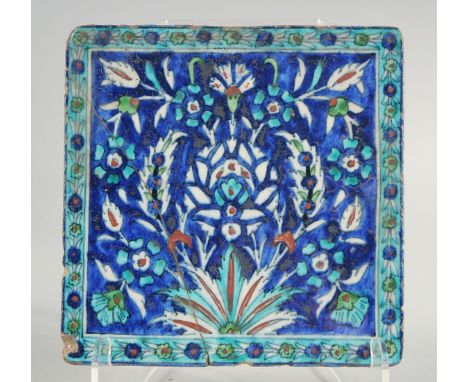 AN IZNIK BLUE AND TURQUOISE GLAZED POTTERY TILE, painted with foliate motifs, 20cm square.