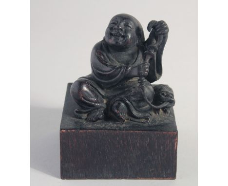 A CHINESE CARVED WOOD IMMORTAL, on a square form base, the base with seal characters, 13cm high.