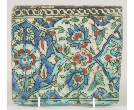 A 18TH/19TH CENTURY IZNIK GLAZED POTTERY TILE, decorated with foliate motifs in blue, turquoise and red, 15cm x 16.5cm.