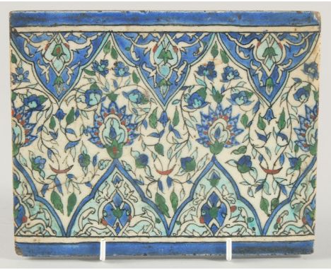 A 18TH/19TH CENTURY IZNIK GLAZED POTTERY TILE, decorated with foliate motifs in blue, turquoise and red, 16cm x 20cm.