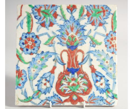 AN IZNIK STYLE GLAZED POTTERY TILE, painted with foliate motifs, 24.5cm square.